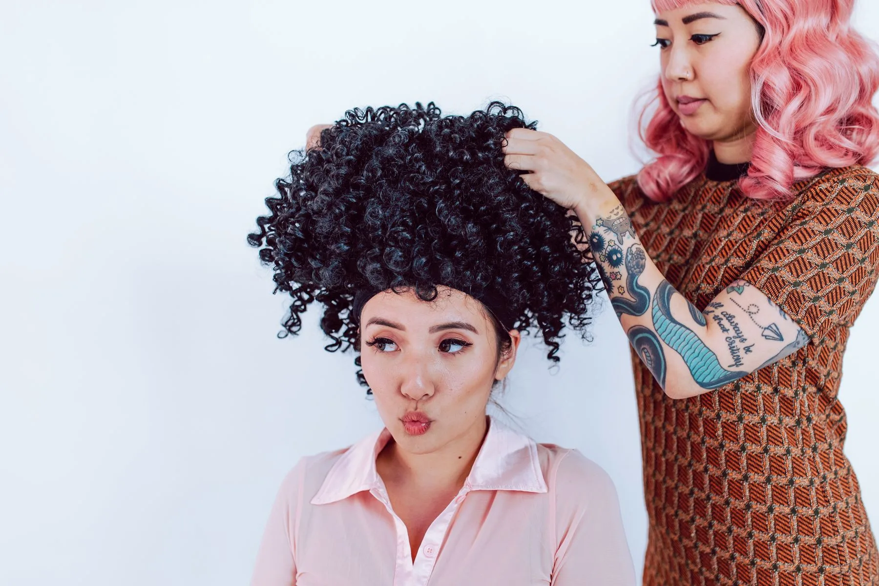 Stylist fitting a curly install on a client in the salon