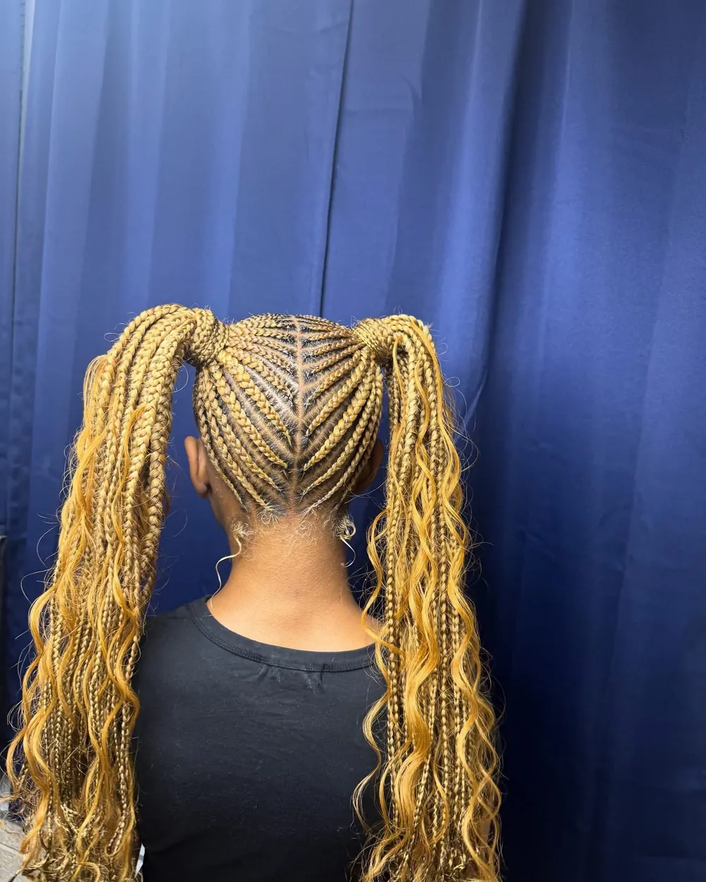 Back view of blonde feed-in braided pigtails with curly ends