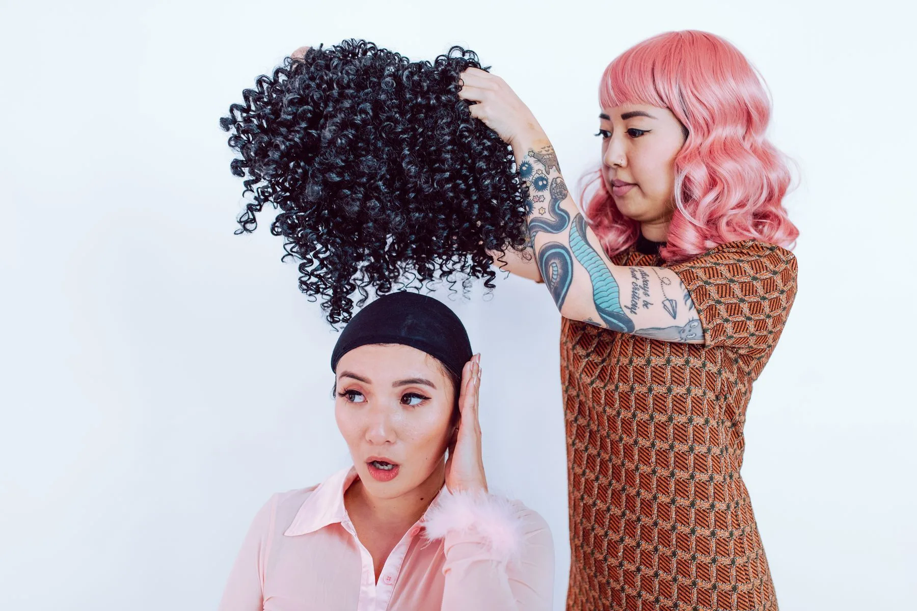Stylist adjusting a curly wig on a client